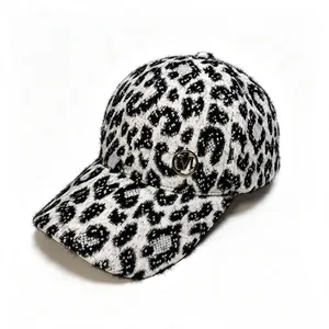 Close-up detail showing the plush leopard print texture and metal M logo on the cap.