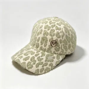 Close-up showing the soft leopard print plush texture and gold M badge on this cap