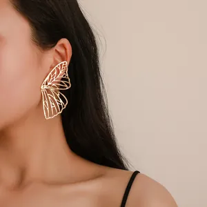 Elegant close-up view of a large hollow golden butterfly wing earring worn by model