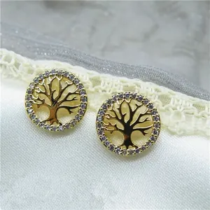 Macro view of gold Tree of Life stud earrings with sparkling crystal border on white lace
