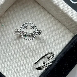 Gros plan sur une bague smiley en argent S925 et une bague à perles multi-rangs argentée