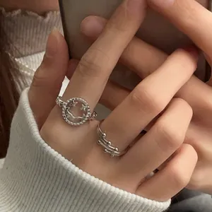 Gros plan d'une bague smiley évidée en argent S925 et d'une bague à perles multi-rangs.