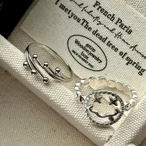 Gros plan sur une bague smiley en argent S925 et une bague à boules sur fond tissu