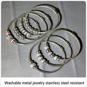 Gros plan de bracelets perlés en acier inoxydable argenté sur un tissu gris texturé
