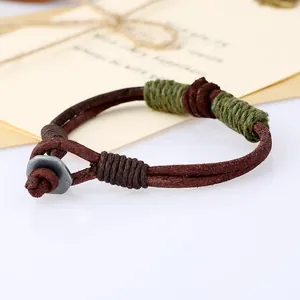 Macro view of a vintage handmade leather woven bracelet with green cord detail.
