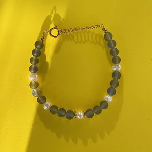 Gros plan sur un bracelet en pierres naturelles grises et perles d'eau douce blanches
