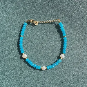 Vue détaillée d'un bracelet en pierres facettées bleues avec trois perλes d'eau douce naturelles.