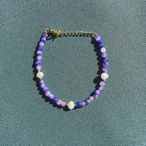 Détail d'un bracelet en perles de pierre naturelle violette et perles d'eau douce.