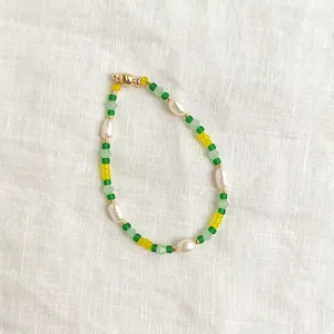 Détail d'un bracelet artisanal avec perles vertes et perles d'eau douce naturelles