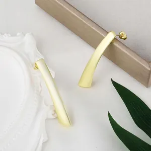 Detailansicht mattgoldener gebogener Stabohrringe mit geometrischem Design