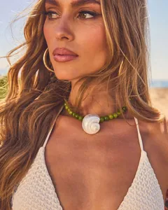 Detailopname van groene kralenketting met een natuurlijke schelphanger bij model
