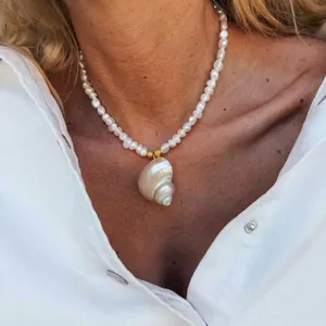 Detail van natuurlijke zoetwaterparelketting met een grote hanger van een zeeschelp