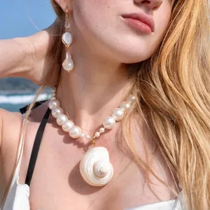 Detail van een natuurlijke zoetwaterparelketting met een schelphanger op een model