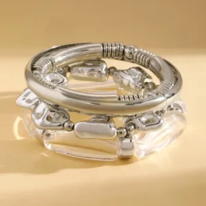 Close-up of stacked metallic silver and clear acrylic irregular bead bracelets for women