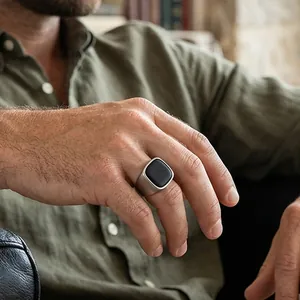 Gros plan d'une bague vintage en acier titane pour homme avec pierre carrée noire