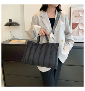 Modella con borsa tote nera trapuntata e tracolla con motivo etnico in un ambiente moderno