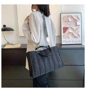 Vista dettagliata della borsa tote trapuntata nera con tracolla a fantasia sul modello.
