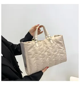 Detailed view of a stylish cream quilted tote bag held by a model in a black blazer
