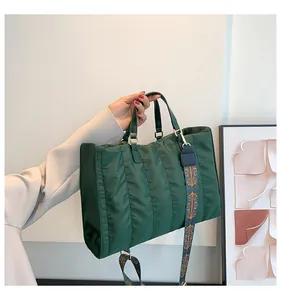 Detailed view of a stylish dark green quilted tote bag with ethnic patterned strap