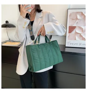 Grande borsa tote trapuntata verde indossata con tracolla a motivi e blazer bianco