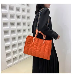 Fashionable large orange quilted tote bag for women shown on a model for autumn and winter