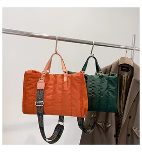 Fashionable large quilted tote bags with patterned straps shown on a display rack