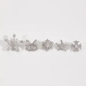 Detalle de cinco clips para la oreja plateados con diseños de estrella y copos de nieve