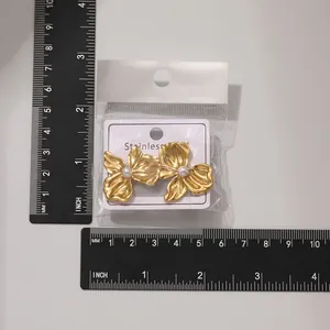 Detailed size view of gold flower pearl earrings with measuring ruler for reference.