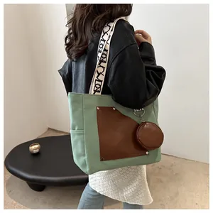 Woman wearing green canvas tote bag with brown leather patch and shoulder strap