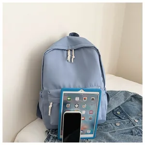 Light blue minimalist backpack shown with tablet and phone for size comparison