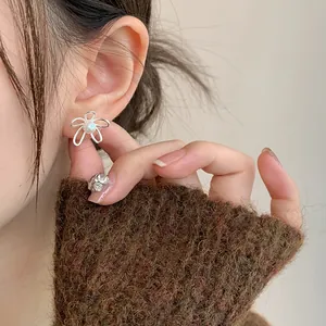Primo piano di un elegante orecchino in argento a forma di fiore e perla su una modella