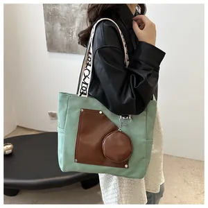 Detail of a mint green canvas tote bag with brown leather pocket and round coin purse.