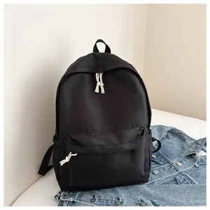 Minimalist black backpack featuring white cord zipper pulls and a stylish denim jacket.