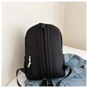 Close-up rear view of a minimalist black Japanese style casual travel backpack for girls