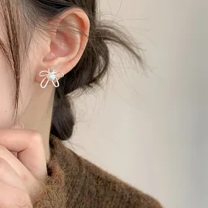 Primo piano dettagliato di orecchini a fiore in argento S925 con perla sull'orecchio.