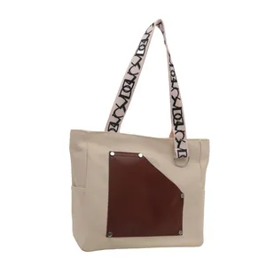 Large canvas tote bag with brown leather pocket and patterned straps for commuting.