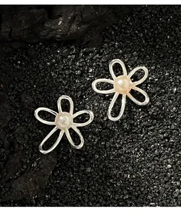 Dettaglio macro di orecchini a fiore in argento con perle su sfondo di roccia scura
