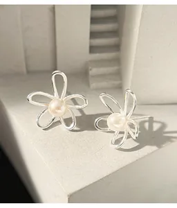 Dettaglio macro di orecchini a fiore in argento irregolari con perla centrale