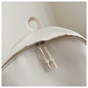 Close-up detail of double zipper with rope pulls on a minimalist cream student backpack