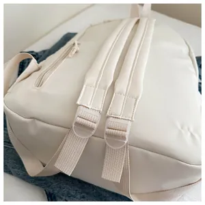 Close-up detail of padded straps on a cream minimalist travel backpack