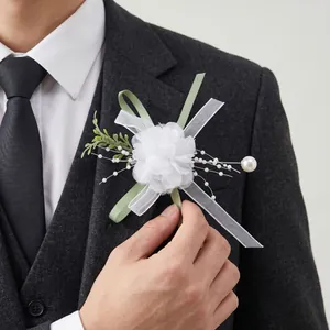 Close-up of white silk boutonniere with green ribbon details on a grey suit jacket