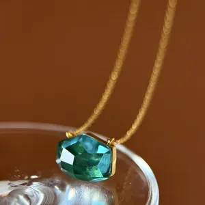 Macro detail showing the irregular faceted cut of an emerald green crystal pendant necklace