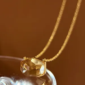 Macro view of a minimalist amber crystal pendant featuring unique irregular facets.