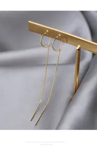 Detailed view of elegant gold long thread earrings on a professional display stand.