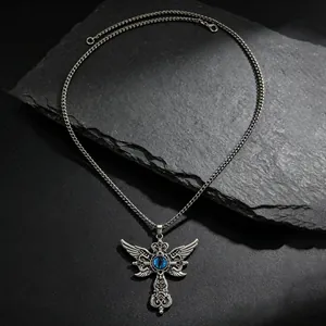 Detalle de collar de cruz gótica con alas y piedra azul sobre una losa de pizarra negra.