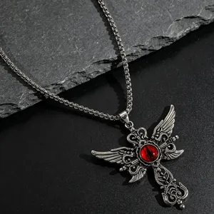 Detalle de un collar gótico de acero inoxidable con cruz alada y un ojo rojo central