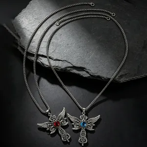 Collares de cruz gótica de acero inoxidable con piedras rojas y azules sobre piedra oscura.