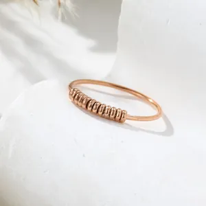 Detailaufnahme eines roségoldenen Titanstahl-Angstrings mit beweglichen Perlen