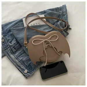 Detailed view of the beige bat wing crossbody bag featuring a unique lace-up design