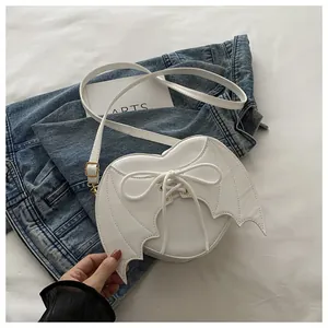 Detailed view of white heart-shaped bag featuring bat wings and a lace-up bow design